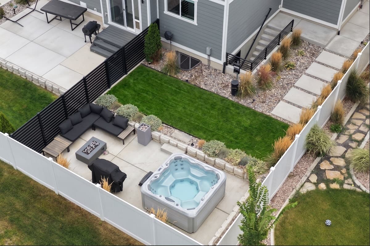 Aerial view of the private fenced backyard with hot tub, fire table and lawn